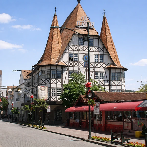 Edifício histórico em estilo medieval com arquitetura de torres pontiagudas em uma rua charmosa, decorada com iluminação de natal e árvores verdes