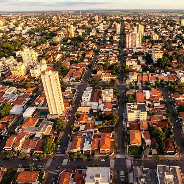 Visão aérea de uma cidade com ruas bem planejadas, edifícios residenciais e comerciais, além de áreas verdes, refletindo urbanização e crescimento urbano no Brasil.