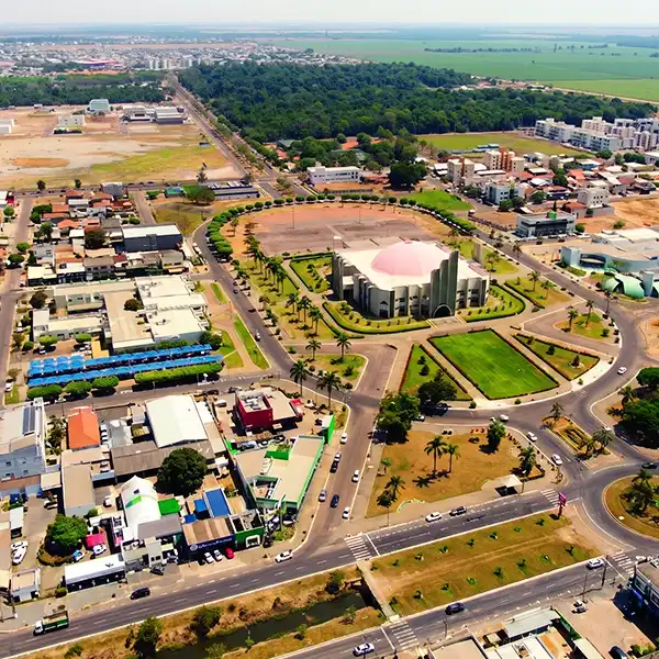 Vista aérea de uma cidade com um parque bem estruturado, destaque para um prédio moderno e áreas verdes, destacando-se na paisagem urbana.